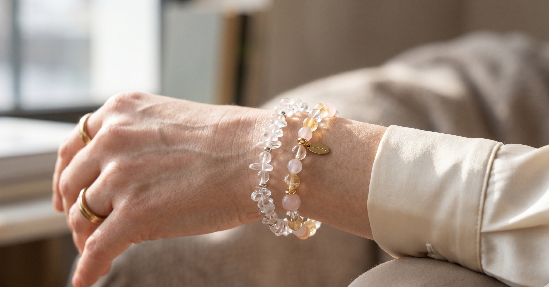 大人の女性の腕元。水晶と色石のブレスレットが美しく重ね付けされている様子