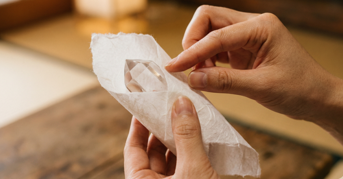 綺麗に浄化された石を白い和紙で優しく包み込む手元